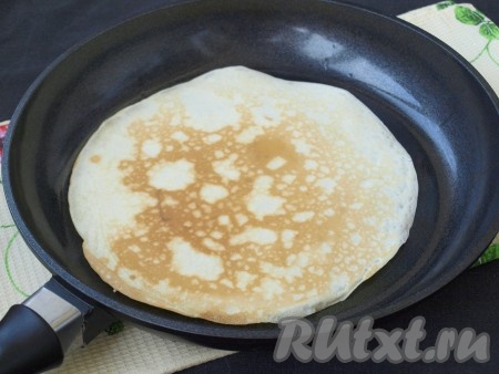 Перевернуть блин и обжарить его до румяности с другой стороны, затем переложить на тарелку. Периодически смазывая сковороду маслом перед жаркой очередного блина, постепенно пожарить все аппетитные блинчики.