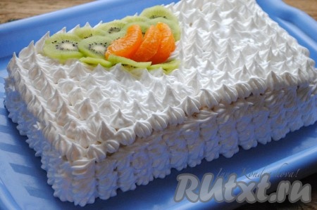 Торт достать из холодильника и украсить белковым кремом. Для красоты я сверху выложила ещё фрукты: киви и очищенные дольки мандарина. Нежнейший бисквитный торт с фруктами и сметанным кремом готов. Отправить его на пару часов в холодильник, чтобы коржи пропитались и можно подавать на стол.&nbsp;
