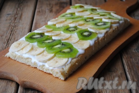 Один бисквитный корж смазать сметанным кремом, сверху выложить фрукты.&nbsp;
