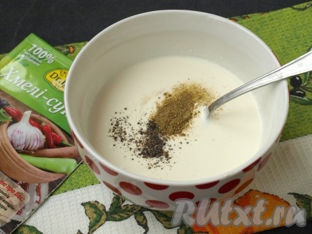 В подходящую ёмкость поместить сметану, добавить по вкусу соль, чёрный перец и приправу хмели-сунели, перемешать.
