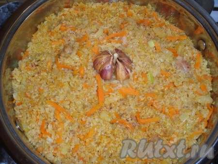 Содержимое сковороды залить, примерно, 1,5 стаканами слегка подсоленного кипятка. Необходимо помнить, что булгур после процедуры промывания уже солоноватый. Сверху поместить тщательно вымытую, неочищенную головку чеснока.
