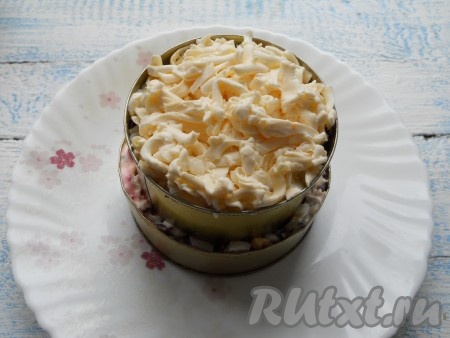 Следующий слой - оставшееся рубленное яйцо + майонез. И последним слоем выложить оставшийся натертый плавленый сыр, майонезом не смазывать.
