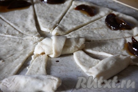 Ближе к основанию треугольника, немного отступив от края, выкладываем повидло и сворачиваем тесто, начиная со стороны с начинкой, формируя рогалик. Аналогично формируем все рогалики.