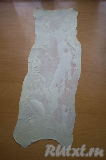 На чистом столе (без муки) раскатываем каждый шарик теста в длинный тонкий прямоугольный пласт, - так тонко, как только получится. Смазываем раскатанный пласт сливочным маслом комнатной температуры (масло должно легко намазываться и распределяться по тесту), затем сворачиваем его в плотный тонкий рулет.