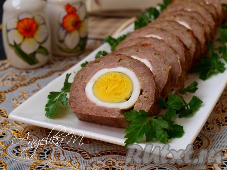 Полностью остывший рулет нарезать на кружочки толщиной около 1,5 см и подать к праздничному столу. На фото видно, как аппетитно выглядит рулет из фарша с вареным яйцом внутри.
