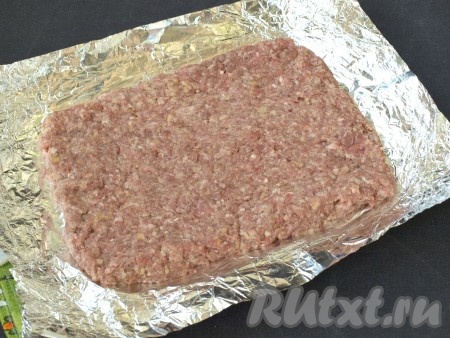 Спустя время разложить на столе фольгу в 2 слоя, выложить мясной фарш в форме прямоугольника.
