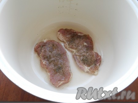 В чашу мультиварки влить оставшееся растительное масло, выложить подготовленные стейки.