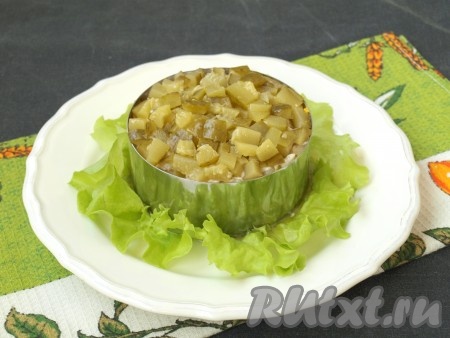 Кубиками нарезать маринованные огурцы и выложить их последним слоем.
