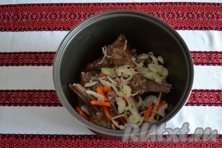 К обжаренным ребрышкам выложить лук с морковью, по вкусу всыпать соль и молотый черный перец.
