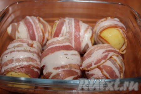 Духовку разогреть до 200 градусов. Выложить картофель в беконе одним слоем в жаропрочную форму и отправить запекаться в разогретую духовку на 35-40 минут (время запекания зависит от сорта и размера картошки). Готовность проверьте вилкой или зубочисткой. Если картофель еще не готов, а бекон уже хорошо подрумянился - накройте форму фольгой.
