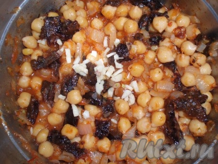 Добавить к нуту нарезанный чернослив и измельченный чеснок, перемешать, потушить еще 5 минут.
