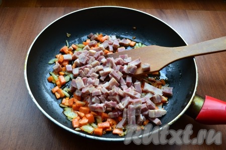 Обжарить овощи, помешивая, около 3-4 минут, после чего добавить к ним нарезанную кубиками ветчину.
