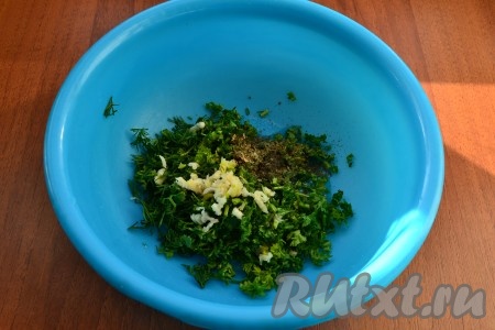 Зелень укропа и петрушки мелко нарезать, добавить пропущенный через пресс чеснок, сушеный базилик и растительное масло, перемешать.
