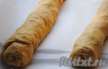 Свернуть в рулет, подвернув внутрь по бокам края теста. Выложить штрудель с квашеной капустой на противень, застеленный пергаментом, швом вниз.&nbsp;
