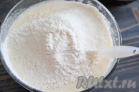 Перемешать массу силиконовой лопаткой. Затем всыпать просеянную муку с разрыхлителем.
