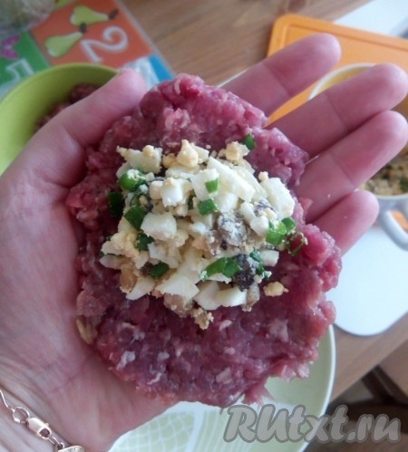 Фарш для этого блюда можно взять покупной или приготовить в домашних условиях, пропустив мясо через мясорубку, посолить и поперчить. Смочить руки холодной водой, чтобы не приставал фарш. На ладонь в виде лепёшки выложить небольшое количество мясного фарша, в середину добавить немного начинки из грибов и яиц.