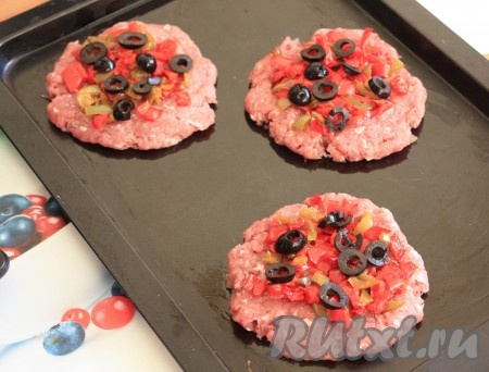 Сверху на мясную лепешку выложить обжаренные перец и лук, нарезанные колечками маслины, смазать майонезом и отправить в разогретую до 200 градусов духовку.