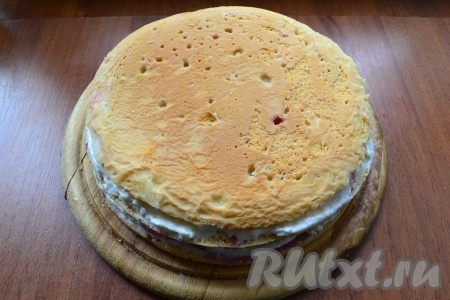 Сверху разместить вторую часть бисквита и также смазать кремом и выложить оставшуюся вишню. Накрыть последней частью бисквита.