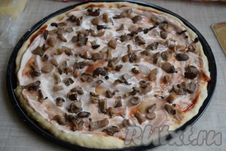 В качестве грибов для этой пиццы я использовала вешенки, которые предварительно были отварены в течение минут 10 в подсоленной воде и заморожены в морозилке. Если грибы замороженные, их нужно разморозить и отжать лишнюю влагу. Если будете готовить с шампиньонами, тогда предварительно отваривать их не нужно, достаточно будет просто промыть водой и нарезать на пластины. Консервированные грибы нужно просто нарезать. Если же для этой пиццы возьмёте свежесобранные лесные грибочки, тогда их нужно будет предварительно отварить в течение 25-30 минут. На смазанное тесто равномерно распределяем половину подготовленных грибов.