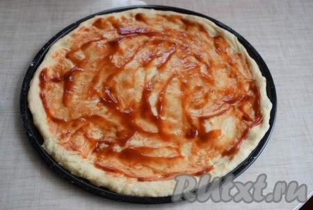 После того как тесто разровняли, смазываем его 1-1,5 столовыми ложками кетчупа.