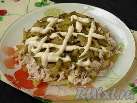 Соломкой нарезать маринованный огурец, выложить его сверху курицы, смазать майонезом.
