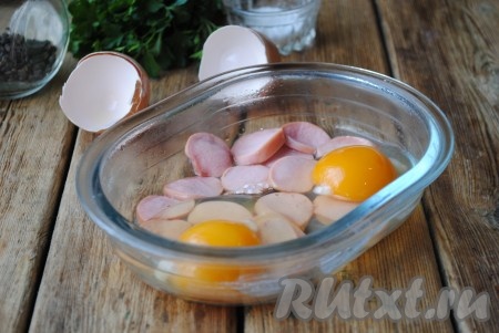 Затем достать форму и поверх сосисок вылить яйца. Аккуратно проколоть желтки зубочисткой (если этого не сделать, желтки могут "выстрелить" в процессе приготовления яичницы в микроволновке).
