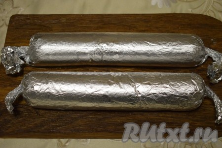 Руками придать шоколадной массе форму колбасы и аккуратно завернуть в фольгу, скатывая из массы колбаску. Скрутить плотно края фольги, чтобы колбаска получилась плотной, однородной и легко резалась. Положить шоколадные колбаски из печенья со сгущенкой в морозилку на 1 час.
