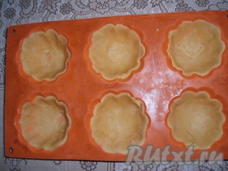 Каждый вырезанный кружочек поместить в формочку для выпечки. Вылепить тестом стенки формочки. Если формы не силиконовые, их перед выкладыванием теста необходимо смазать маслом.