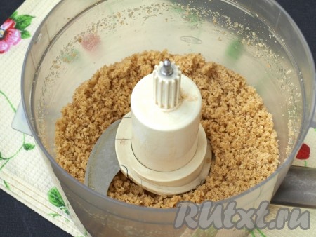 В чашу комбайна поместить поломанное на кусочки печенье и измельчить при помощи насадки "металлический нож". К крошке добавить растопленное сливочное масло и перекрутить ещё раз, чтобы крошка стала влажной.