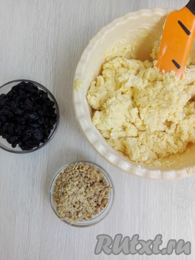 Сухие ингредиенты всыпать в получившуюся творожную массу и перемешать лопаткой. Добавить орехи, предварительно запаренный и обсушенный изюм, перемешать.