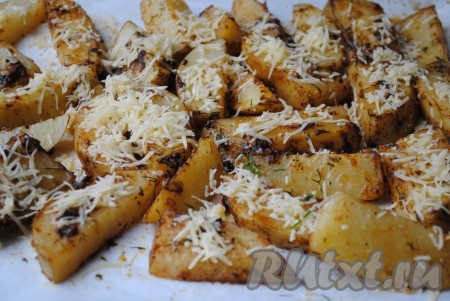 Затем достать противень с запечённой молодой картошкой из духовки, посыпать натёртым сыром. Запекать ещё 10 минут (до румяной сырной корочки).&nbsp;