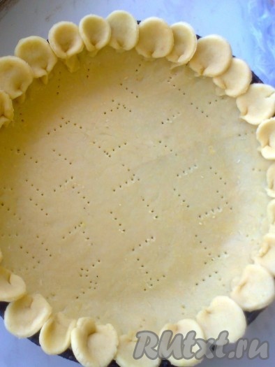 Раскатать тесто в круг. Дно формы смазать растительным маслом или застелить бумагой для выпечки, выложить тесто, распределить его по форме, формируя бортики высотой 2-3 см. Наколоть тесто вилкой. Обрезать ровно края теста. Из обрезанных остатков теста вырезать рюмкой кружочки, соединить края кружочков внизу и украсить обрезанные края теста, выложив на них кружочки,
