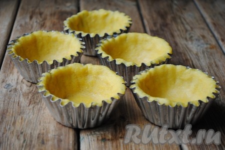 Из теста вырезать круги по размеру на&nbsp;пару сантиметров больше диаметра формочек. Выложить тесто в формочки, прижимая ко дну и стенкам. Я выпекала в металлических формочках, предварительно их ничем не смазывала и не застилала. Тесто (и по бокам, и на дне формочек) наколоть вилкой.
