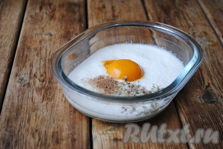 В миску с кефиром и содой вбить яйцо, добавить соль, чёрный молотый перец и итальянские травы. 