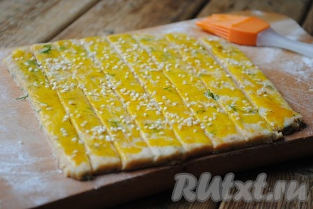 Смазать полоски взбитым яйцом и посыпать кунжутом.