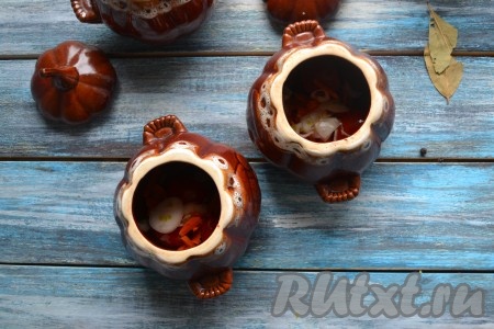 Равномерно распределяя, выложить в горшочки половину лука и моркови.
