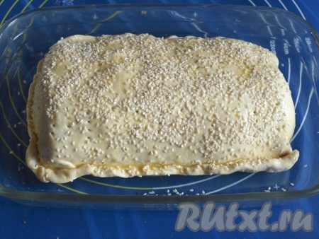 Форму для запекания смазать растительным маслом, поместить в неё мясо в тесте. Смазать тесто взбитым яйцом и посыпать кунжутом.