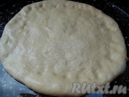 Смажьте противень растительным маслом. Тесто слегка обомните, растяните его руками и положите на противень. Далее растягивайте тесто по кругу, прижимая ладошками.