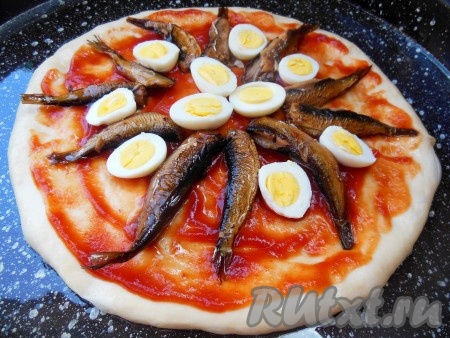 На тесто, смазанное кетчупом, по кругу разложите шпроты, между ними разместите нарезанные вареные яйца.
