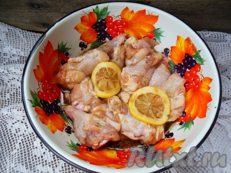 Добавьте к куриным крылышкам колечки лимона, выдавливая из них сок, залейте маринадом и перемешайте. Чеснок в шелухе разрежьте на две части и выложите к мясу. Оставьте крылышки мариноваться, примерно, на час, можно оставить в холодильнике и на более длительное время.
