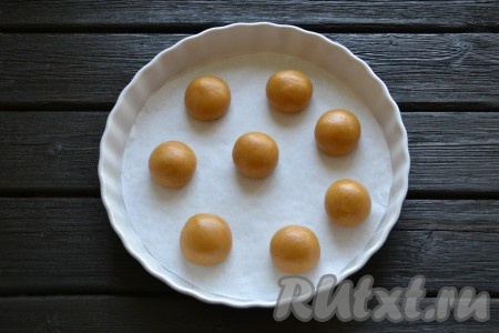 От общего куска теста отобрать кусочек теста весом 45 грамм и скатать из него шарик между двумя ладошками. Аналогично сформировать шарики из оставшегося теста. Форму для запекания застелить пекарской бумагой и на нее выложить скатанные шарики из теста (на небольшом расстоянии друг от друга).
