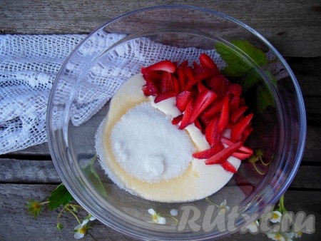 В сметану добавьте сахар и нарезанные ягоды.