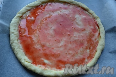 Готовое тесто на присыпанной мукой поверхности раскатать в круг толщиной около 0,5 сантиметра, сформировав бортики. Поместить тесто на противень, застеленный пергаментом и присыпанный немного мукой. Смазать тесто любым джемом (бортики не смазывать).