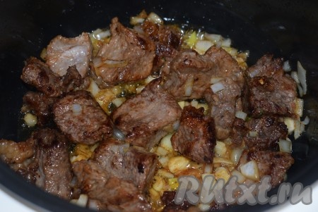 Когда мясо подрумянится, добавляем к нему нарезанный лук и измельченный чеснок. Жарим с открытой крышкой мультиварки еще минут 10 (до золотистого цвета лука), иногда помешивая.