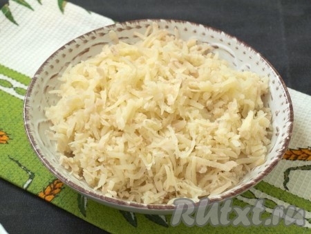 Картофель хорошо вымыть, выложить в кастрюлю, не очищая от кожуры (то есть в "мундирах"), залить полностью водой, поставить на огонь. После закипания воды отварить картошку до готовности (в зависимости от величины картошин и сорта на варку потребуется 25-35 минут, готовые картошины будут легко прокалываться вилкой). Варёный картофель остудить, очистить от кожуры и натереть на крупной тёрке в глубокую тарелку.