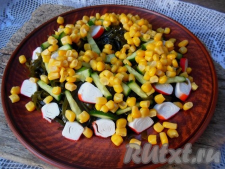 Добавьте кукурузу к морской капусте, крабовым палочкам и огурцам.