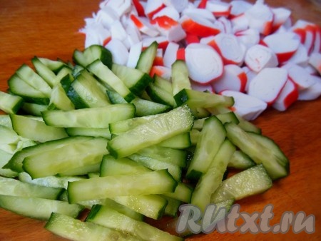 Крабовые палочки нарежьте слегка наискосок, огурец - тонкими брусочками.
