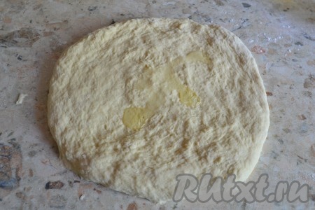 На столе, присыпанном мукой, тесто растянуть руками, смазать тесто растительным маслом.
