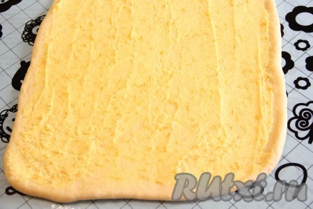 Теперь приготовим лимонную начинку для нашего дрожжевого пирога. Сливочное масло нужно предварительно достать из холодильника, чтобы оно согрелось при комнатной температуре и стало мягким. Лимон хорошо вымыть, обсушить, а затем снять с него цедру, не затрагивая находящийся под ней белый слой. Соединить масло, цедру лимона и сахар, всё тщательно перемешать. Смазать пласт теста получившейся начинкой.