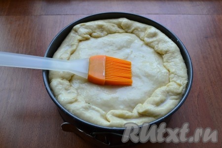 Меньшую часть теста раскатать по диаметру формы и накрыть тестом пирог. Края нижней части теста завернуть вовнутрь и немного защипнуть стыки. Смазать пирог сверху теплым молоком.
